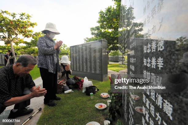 People pray in front of the Cornerstone of Peace where the names of their bereaved family members and relatives engraved at the Peace Memorial Park...