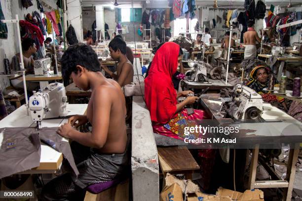 Man, Woman, Children sews a cloth in a local garment shop in Dhaka, Bangladesh. World Day Against Child Labor was observed on 12 June across the...
