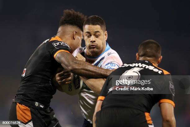 Kevin Naiqama and Tu'imoala Lolohea of the Tigers tackle Jarryd Hayne of the Titans during the round 16 NRL match between the Wests Tigers and the...