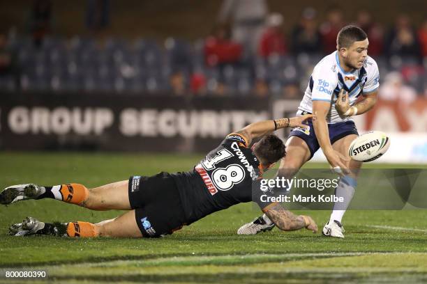 Ashley Taylor of the Titans loses the ball as he is tackled by Malakai Watene-Zelezniak of the Tigers during the round 16 NRL match between the Wests...