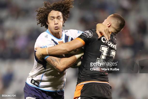 Kevin Proctor of the Titans is tackled by Kyle Lovett of the Tigers during the round 16 NRL match between the Wests Tigers and the Gold Coast Titans...