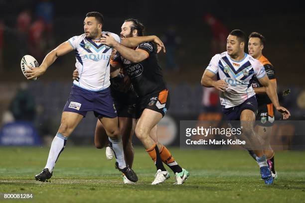 Ryan James of the Titans passes as he is tackled by Aaron Woods of the Tigers during the round 16 NRL match between the Wests Tigers and the Gold...