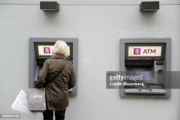 Pedestrian uses an automated teller machine outside a bank branch of Allied Irish Banks Plc in Dublin, Ireland, on Friday, June 23, 2017. Ireland...