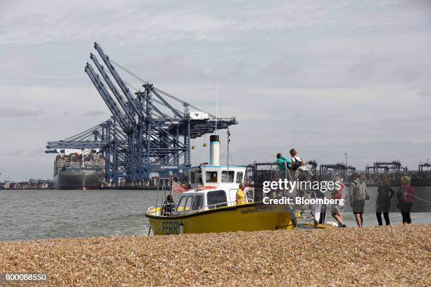 Pedestrians board a ferry to take a trip to see the Orient Overseas Container Line's Hong Kong container ship anchored dockside at the Port of...