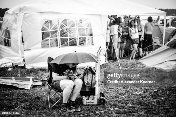 Festival goers sits under an umbrella ahead the Hurricane Festival 2017 on June 22, 2017 in Scheessel, Germany. The area of the festival was hit by...