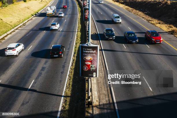 Automobiles pass an advertisement for the Wild Bean Cafe on the central reservation of the M1 freeway in Johannesburg, South Africa, on Thursday,...