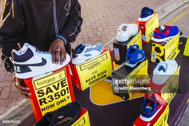Vendor sells Nike Inc. And Adidas AG footwear for a local retail store on a street stall near a footbridge in the Sandton district of Johannesburg,...