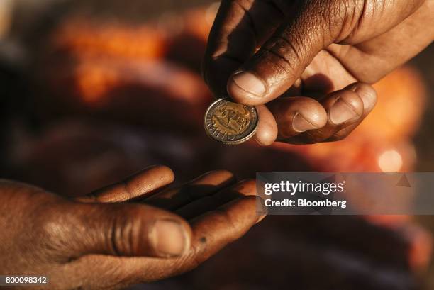 Customer hands over a five rand coin at a 'spaza' store on a sidewalk in the Sandton district of Johannesburg, South Africa, on Thursday, June 22,...