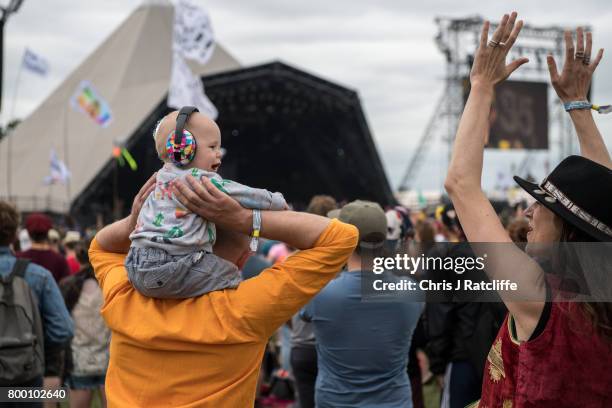 Family with a baby wearing ear defenders on his fathers shoulders watch Hacienda Classical on the Pyramid stage at Glastonbury Festival Site on...