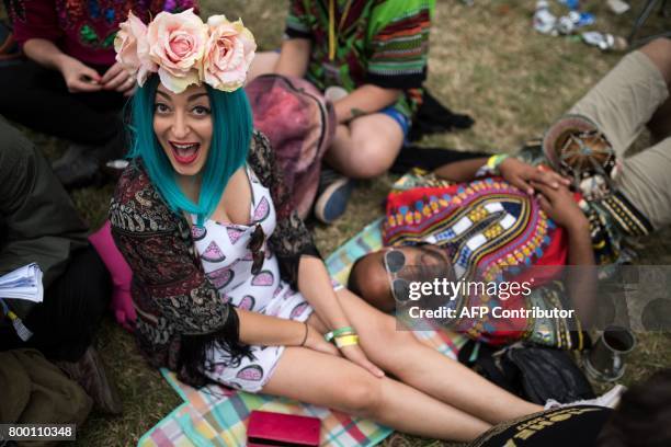 Music fans rest on the grass in front of the Pyramid Stage at the Glastonbury Festival of Music and Performing Arts on Worthy Farm near the village...