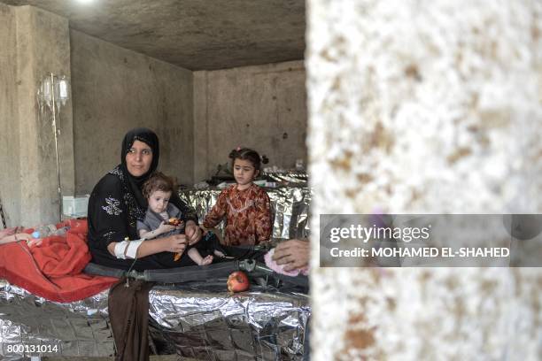 An Iraqi woman and children, who suffered injuries following a suicide attack as they were escaping the Old City of Mosul, wait to receive treatment...