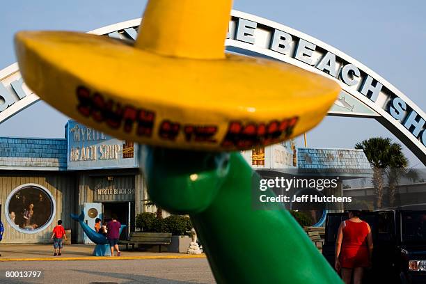 Green dinosaur wears a South of the Border sombrero in front of the Myrtle Beach trinket shop as tourists load back into their cars at South of the...