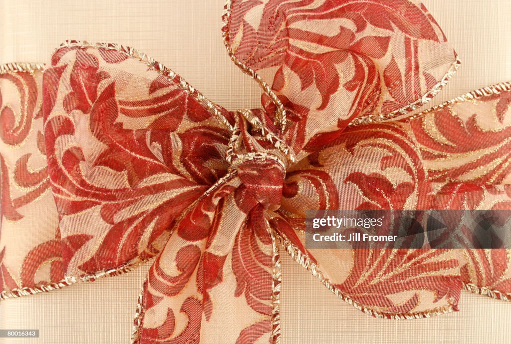 Close up of a gold gift with a burgundy and gold ribbon.