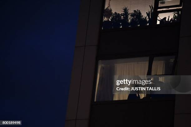 Residents looks out of a window from the Taplow Tower residential block on the Chalcots Estate in north London on June 23, 2017 as other residents...