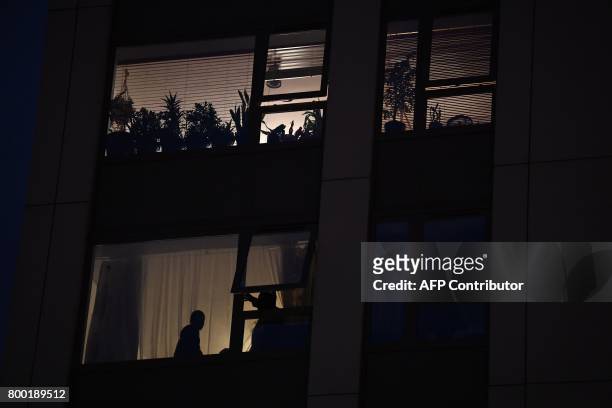 Residents looks out of a window from the Taplow Tower residential block on the Chalcots Estate in north London on June 23, 2017 as other residents...