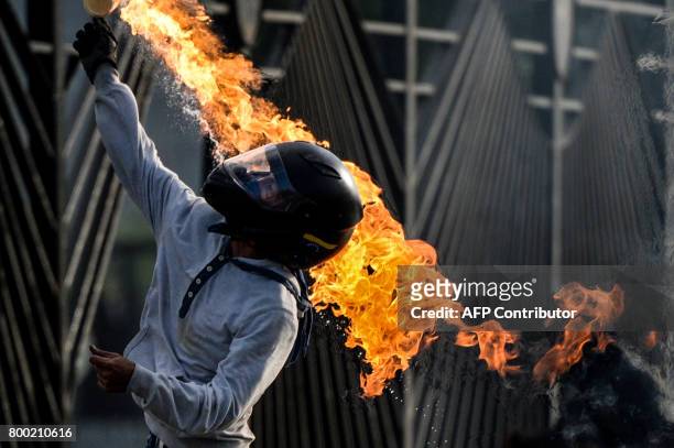 An opposition activist throws a molotov cocktail as demonstrators blocking a highway in Caracas clash with police during a protest against the...