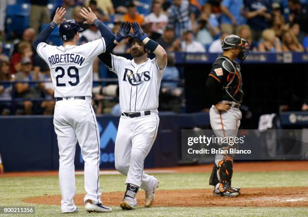 Derek Norris of the Tampa Bay Rays celebrates with Daniel Robertson of the Tampa Bay Rays in front of catcher Welington Castillo of the Baltimore...