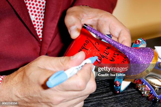 Christian Louboutin signs shoes during the Christian Louboutin Store Opening on June 23, 2017 in Munich, Germany.