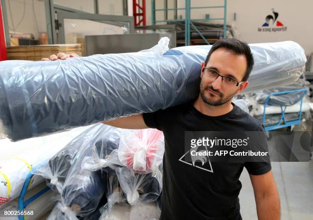Am employee carries a textile roll, at the sewing studio of the production plant of the French sport clothing and equipment brand Le Coq Sportif, in...