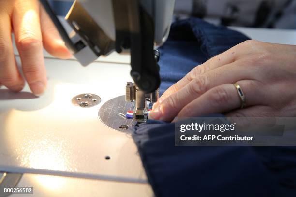 An employee sews, thanks to a sewing machine, at the sewing studio of the production plant of the French sport clothing and equipment brand Le Coq...