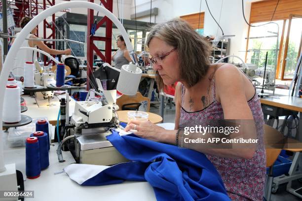 An employee sews, thanks to a sewing machine, at the sewing studio of the production plant of the French sport clothing and equipment brand Le Coq...