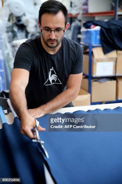 An employee works on textiles, at the sewing studio of the production plant of the French sport clothing and equipment brand Le Coq Sportif, in...