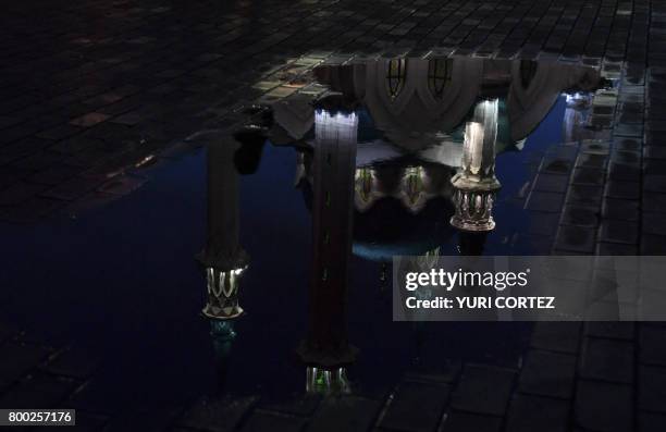 The illuminated Qolsarif Mosque is seen reflected in a puddle during the Russia 2017 Confederations Cup football tournament in Kazan on June 23, 2017.