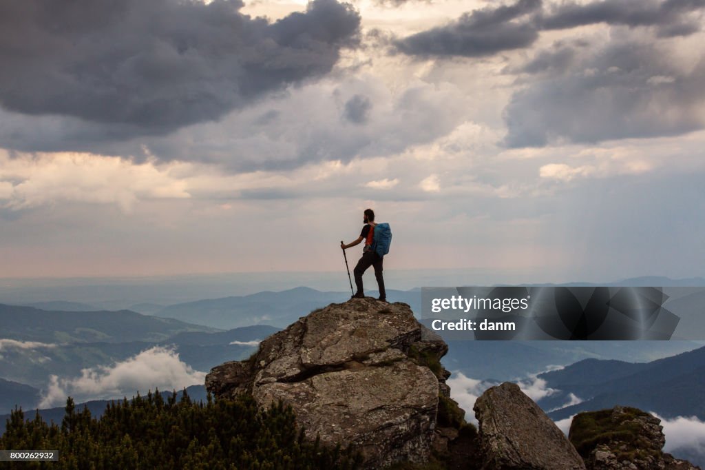 Trekker hiking on a mountain with beautiful storm clouds in background