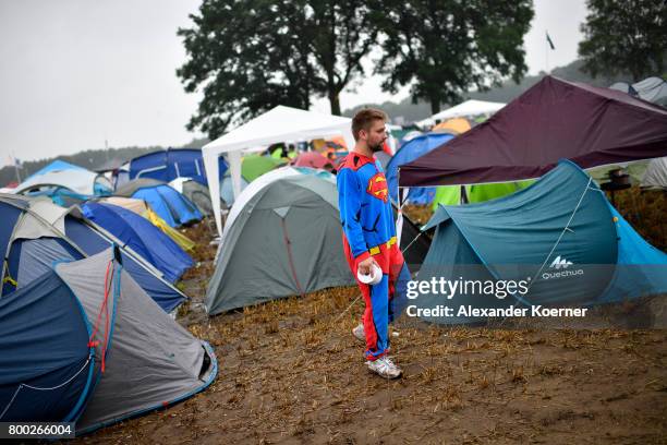 Festival goer wearing a superman costume walks through rain and mud at the camp site of the Hurricane Festival 2017 after a night full of heavy rain...