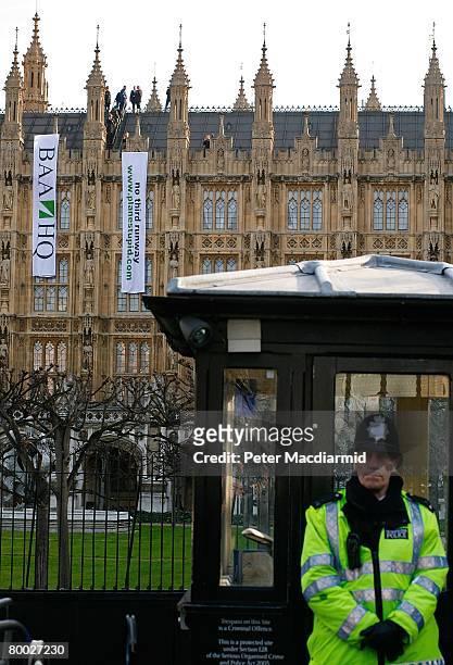 Policeman stands guard while the protestors calling for a halt to the Heathrow airport expansion scale the roof of the Houses of Parliament on...