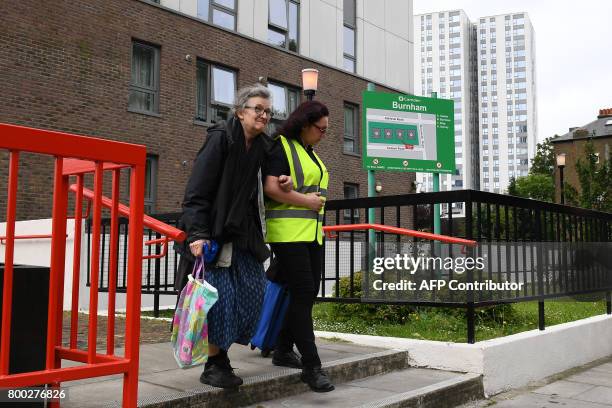 Resident is helped by a council official as she leaves Burnham Tower residential block on the Chalcots Estate in north London on June 24, 2017 as...