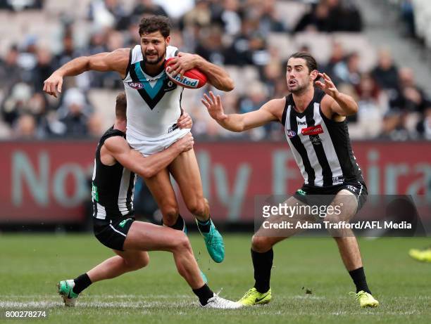 Paddy Ryder of the Power is tackled by Taylor Adams of the Magpies while Brodie Grundy of the Magpies looks on during the 2017 AFL round 14 match...