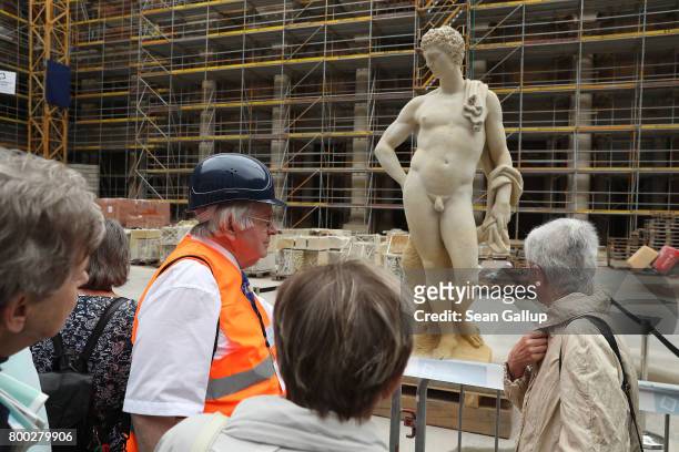 Guide leads visitors to a statue during open house day at the construction site of the Berlin City Palace, which will house the Humboldt Forum, on...