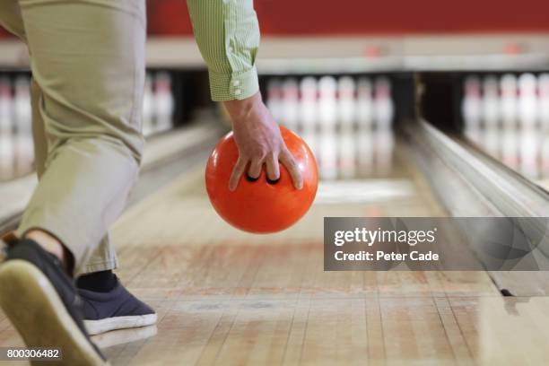 man about to bowl orange bowling ball - bowlingkugel stock-fotos und bilder