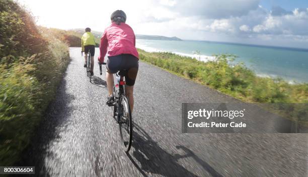 couple cycling on coastal road - coastal road stock pictures, royalty-free photos & images