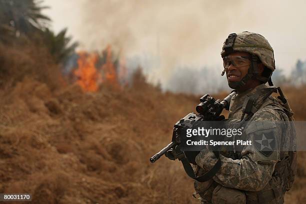 Sgt. Jonathan Silva-Mateo with the Army 2-1 Cavalry and of Miami Beach, Florida keeps watch over burning brush February 27, 2008 in Diyala Province,...