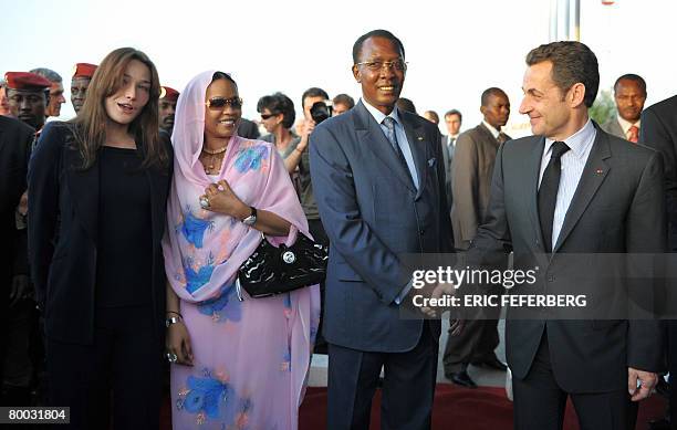 French President Nicolas Sarkozy shakes hands with his Chad's counterpart Idriss Deby Itno as his wife Carla Bruni-Sarkozy talks with Chad first lady...