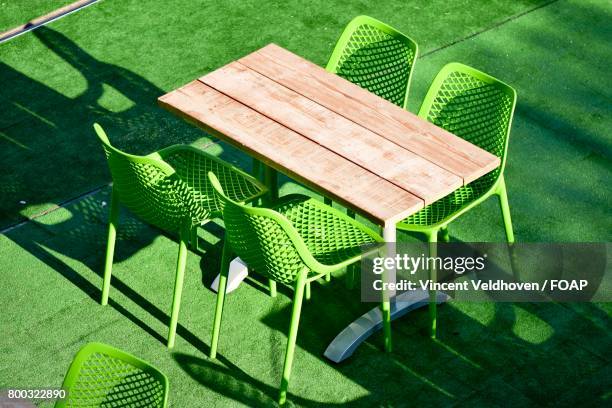 green chair with wooden table - abscess stockfoto's en -beelden