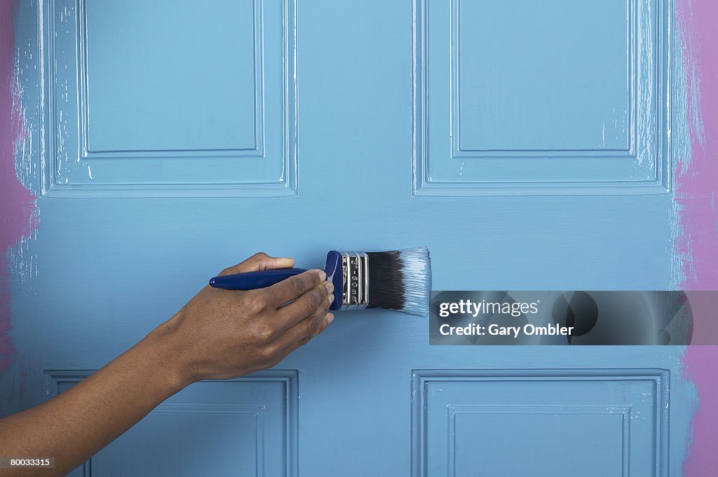 Applying blue paint to a door with a brush