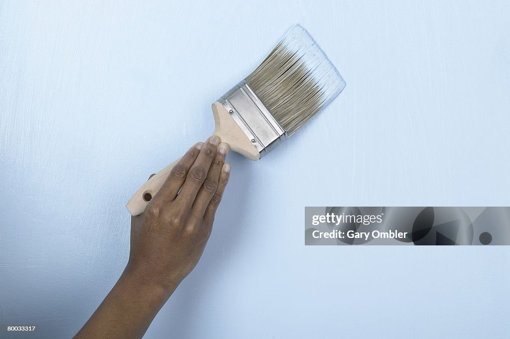 Applying blue paint to a wall with a brush
