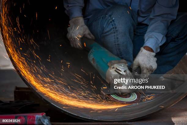 manual worker on a workshop grinding big steel pipe - blacksmith sparks stock-fotos und bilder