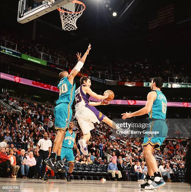 Steve Nash of the Phoenix Suns jumps up to pass the ball around David West and Peja Stojakovic of the New Orleans Hornets during the game on February...