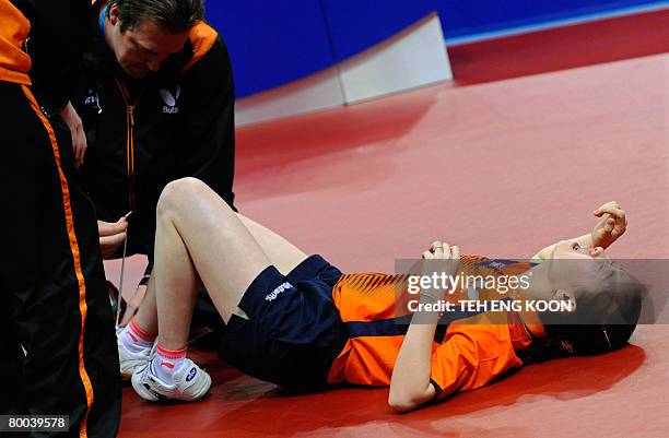 Trainer attends to the injured foot of Li Jie of the Netherlands during the women's quarter-final match at the World Team Table Tennis Championships...