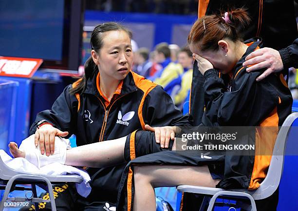 The Netherland's Li Jiao comforts her teammate Li Jie after she injured her foot during her women's quarter-final match against Singapore at the...