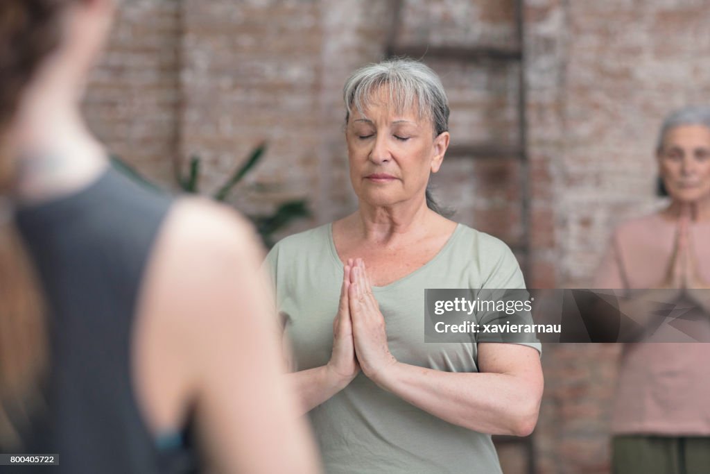 Senior woman practicing yoga in prayer position