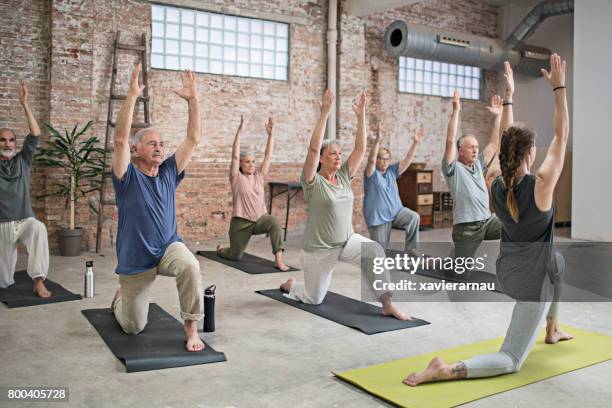 senior people and coach doing warrior pose in gym - pensioners demonstrate in spain stock pictures, royalty-free photos & images