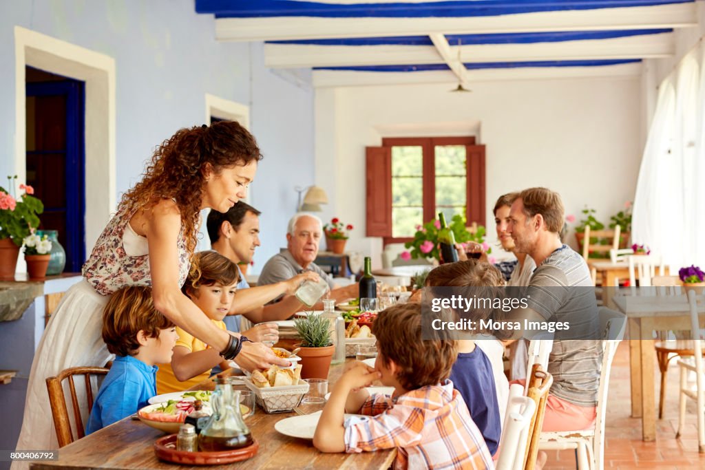 Madre que sirven comida a los niños en la mesa