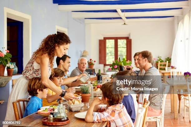 mother serving food to children at table - pranzo foto e immagini stock