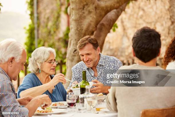 senior woman serving food to man at table in yard - grandma son stock pictures, royalty-free photos & images