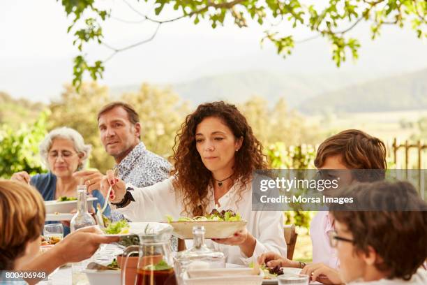 woman serving food to children at table in yard - family lunch stock pictures, royalty-free photos & images